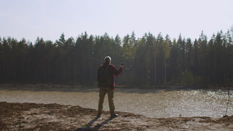 inspired man on high shore of river is enjoying and admiring nature back view of male figure fisherman with rod