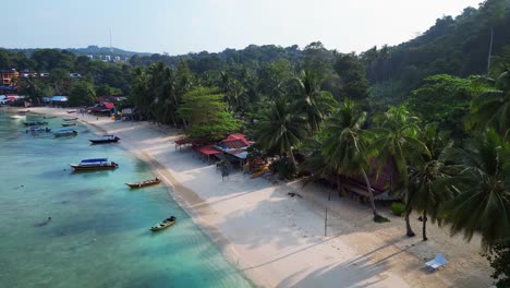 Humor-Matutino-Vista-Aérea-Rampa-De-Velocidad-De-Una-Isla-Tropical-Con-Un-Largo-Muelle-De-Madera-Que-Conduce-A-Un-Restaurante-Flotante,-Rodeado-De-Aguas-Turquesas-Y-Una-Exuberante-Selva-Tropical