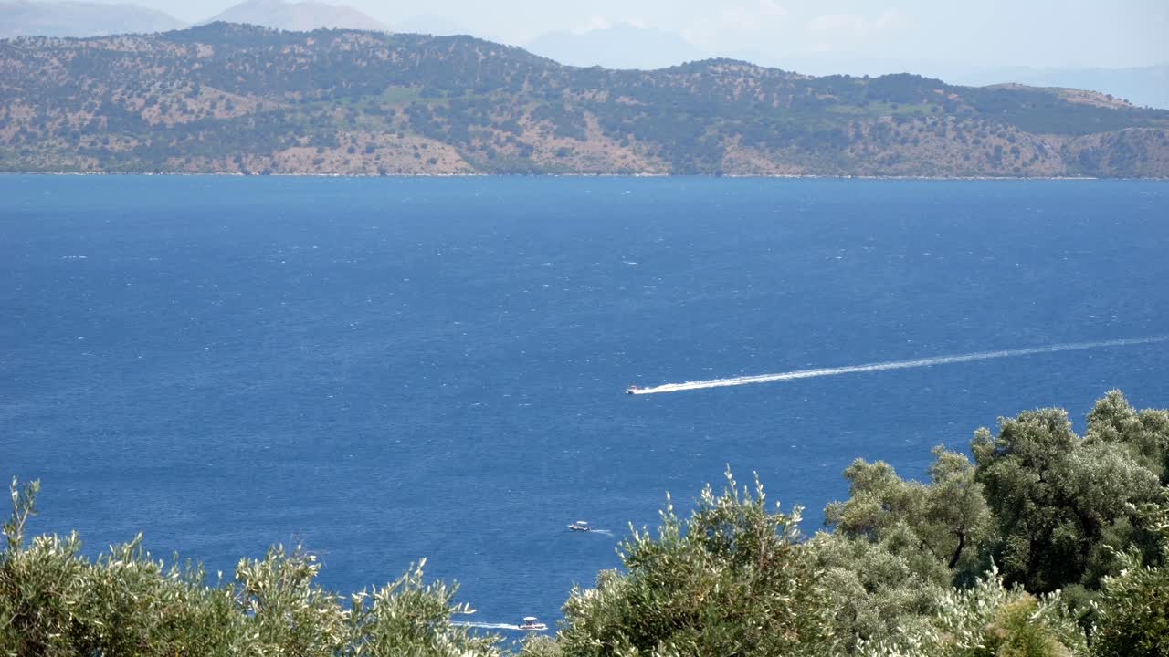 barco de motor navegando en las aguas azules del mar jónico cerca de la isla de corfú, con altas montañas en el fondo