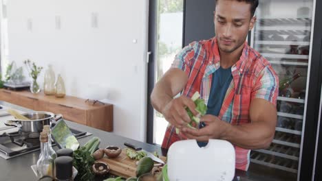 hombre biracial preparando comida, compostaje de residuos vegetales en la cocina moderna, espacio de copia, cámara lenta