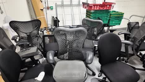 Multiple used office chairs in a basement storage area, signaling clutter and reuse.