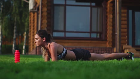 hermosa morena en el fondo de una gran mansión dedicada al fitness y realiza ejercicios de tabla para la prensa