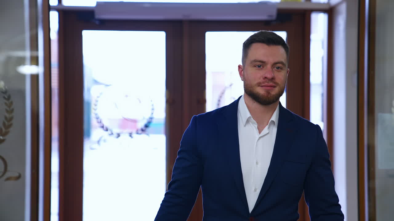 Young businessman coming into the hotel. Portrait of a handsome bearded man in costume entering the lobby and walking in luxury hotel.