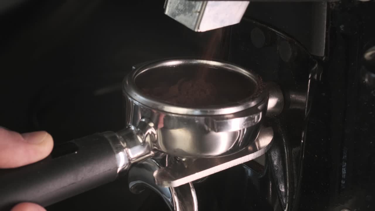 Ground coffee powder being dispensed into a portafilter, ready for brewing fresh espresso