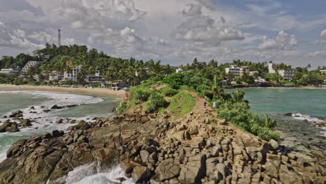 mirissa sri lanka aerial v5 cinematic drone fly around parrot rock at low tide capturing beautiful seascape, bandaramulla beachfront resort hotels along the shore - shot with mavic 3 cine - april 2023