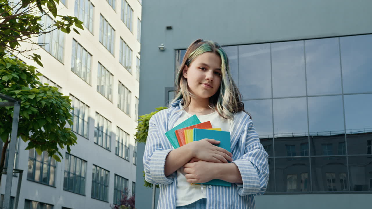 una adolescente con libros afuera de un edificio