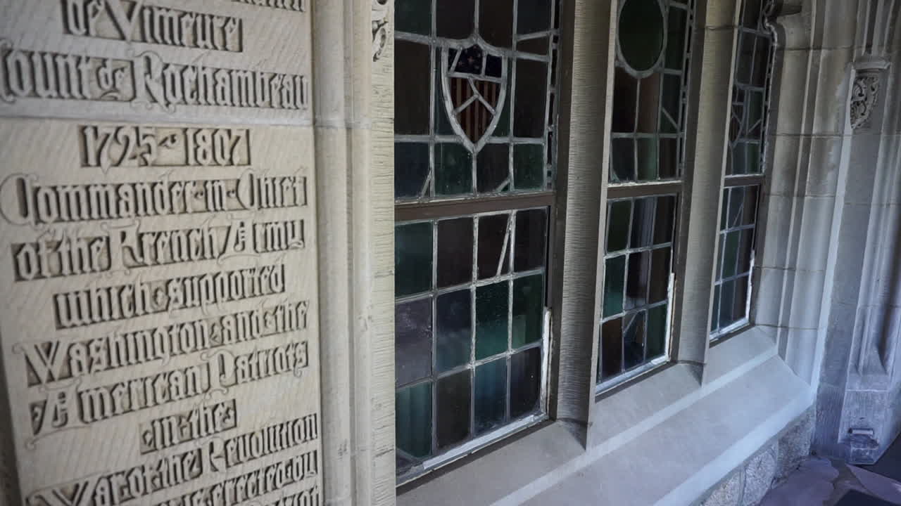 Camera tilts down on leaded glass window with tracery and gothic script wall inscription
