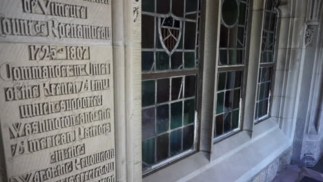 camera tilts down on leaded glass window with tracery and gothic script wall inscription