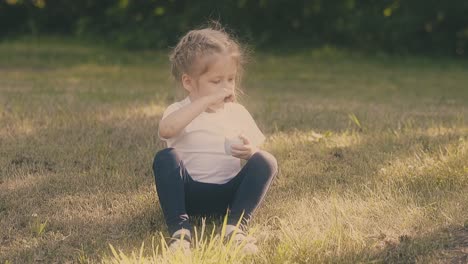 nice little girl with fair hair eats fresh yogurt with spoon