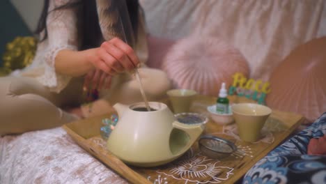 spiritual woman preparing tea using a feather and natural herbs for healing