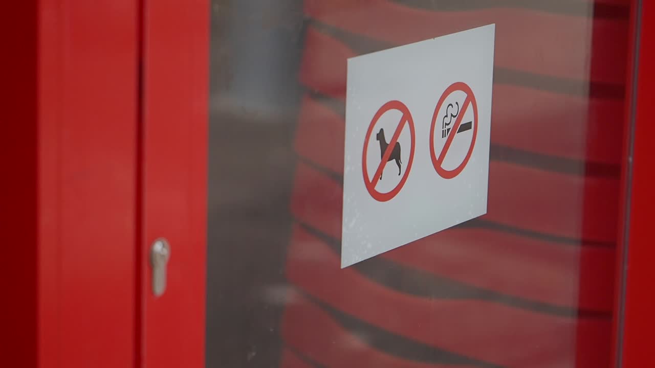 Cartelli di divieto (niente cani e niente fumo) su porta a vetri