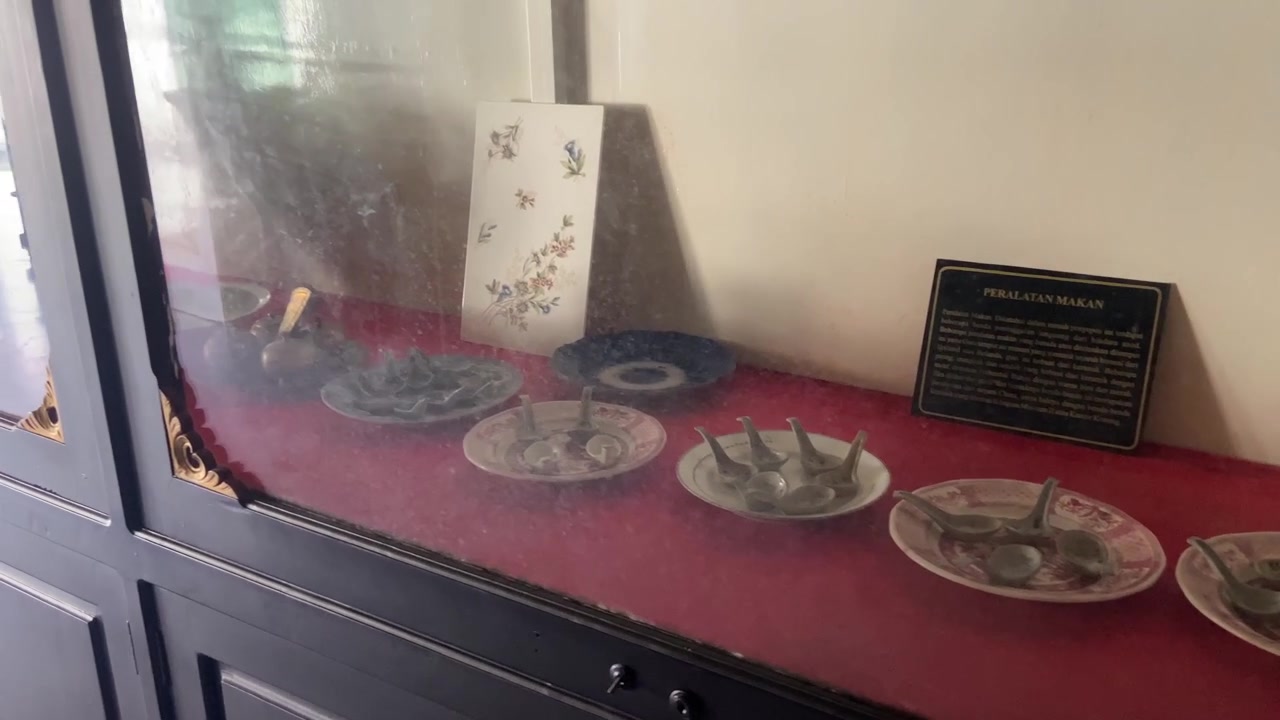 Antique Eating Utensils and Plates Displayed in a Museum Case