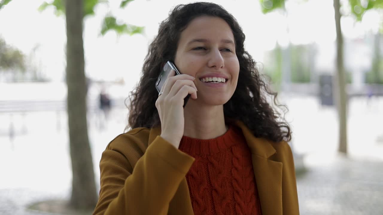 mujer sonriente hablando por teléfono celular al aire libre