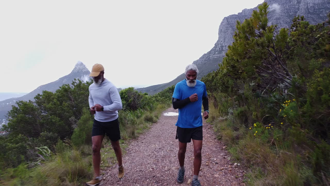 Two men running on a trail in the mountains