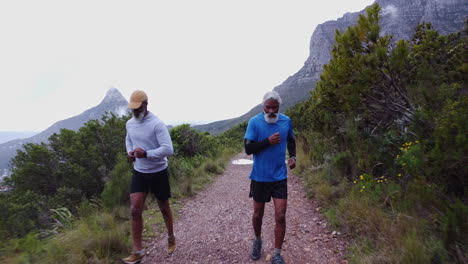 two men running on a trail in the mountains
