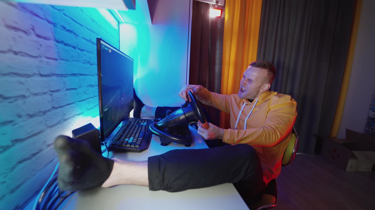 Driving game simulator. Side view of young man enjoying car racing video game