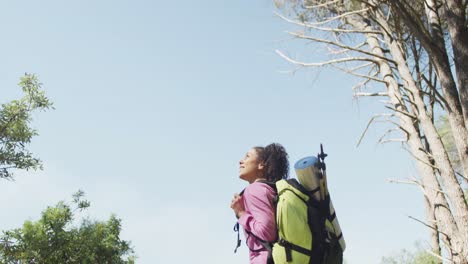 Smiling-biracial-woman-looking-away-and-hiking-in-countryside