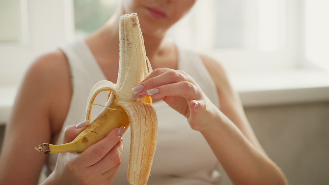 Woman peeling and eating a banana