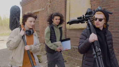 four coworkers holding material for a recording as they enter a ruined building