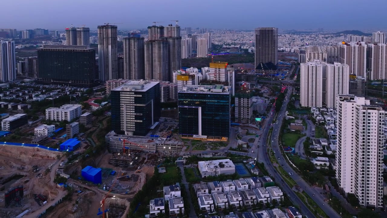 Edificio Phoenix con edifici a torre in costruzione, ville, skyline e strada nel quartiere finanziario, Nanakramguda, Hyderabad, Telangana, India. Di giorno, ripresa ad arco, ripresa con drone, 4k