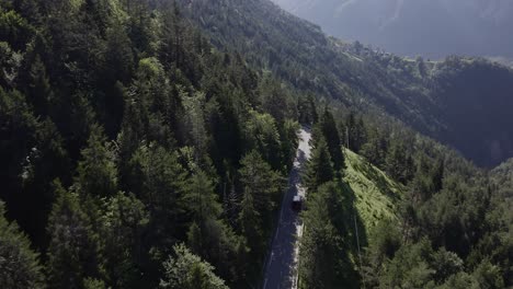 Enthüllung-Eines-Roten-Minivans,-Der-An-Einem-Sonnigen-Morgen-Einen-Steilen-Berg-Entlang-Durch-Den-Wald-In-Den-Alpen-Fährt---Drohne-Folgt-Der-Kamera