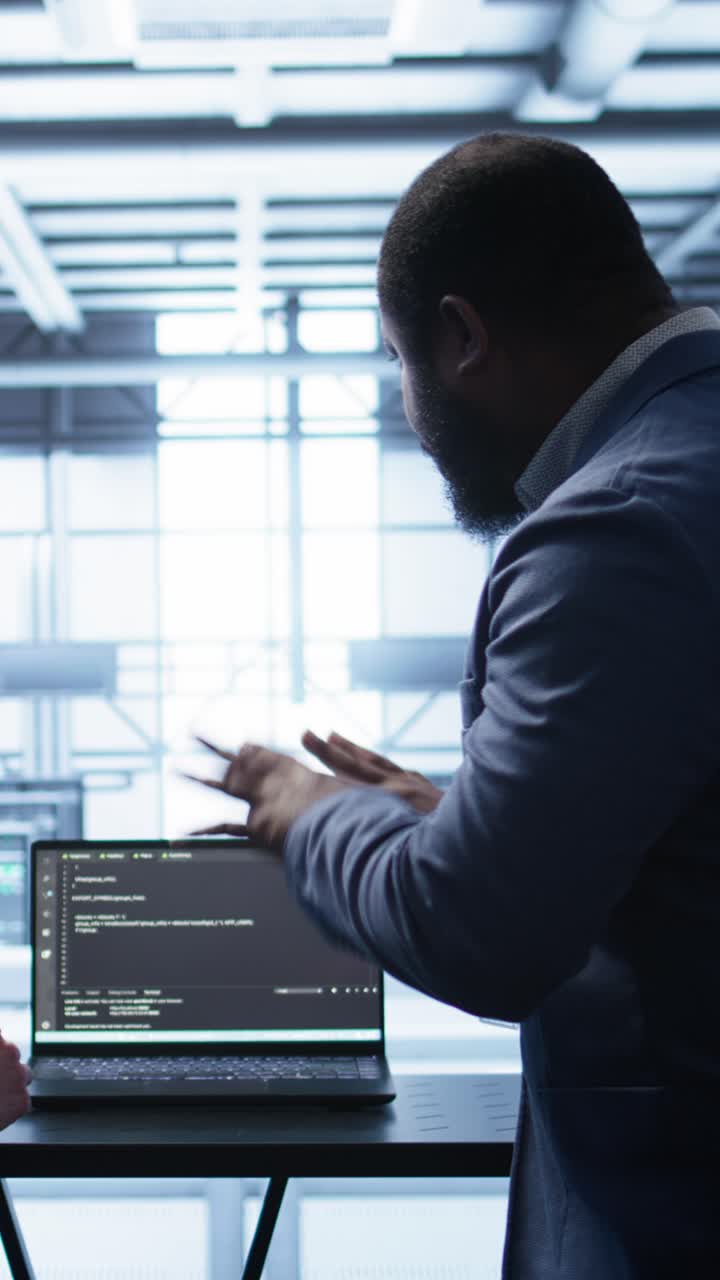 IT Professional Explaining Code on Laptop in High-Tech Environment