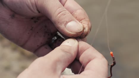 male hands fisherman preparing bait and fishing worm on hook close up