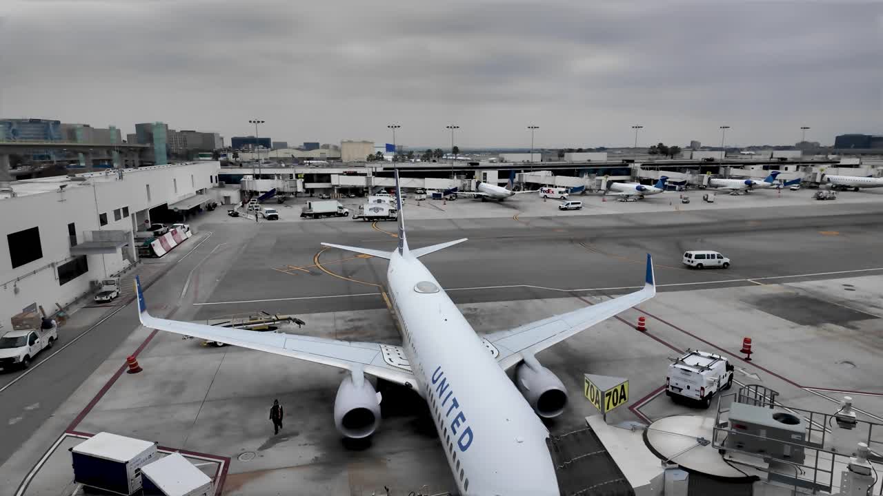 Airport tarmac with United Airlines airplane and ground vehicles under a cloudy sky