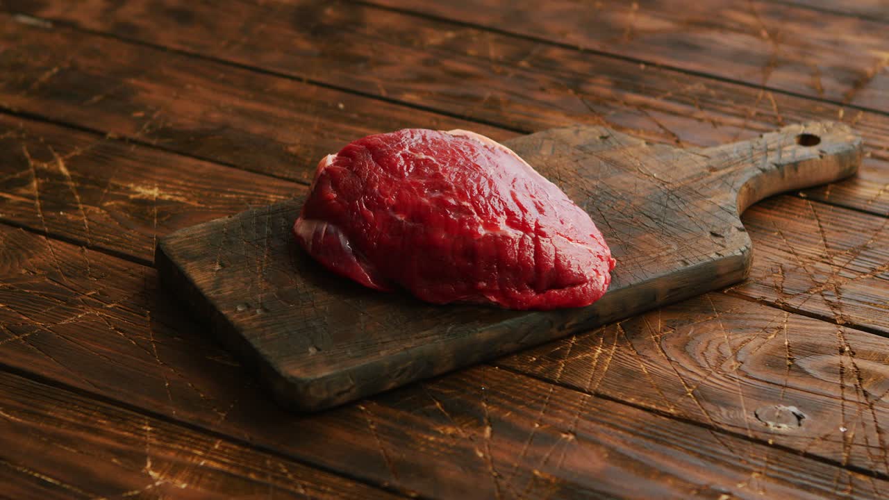 Big fresh piece of meat laid on wooden cutting board