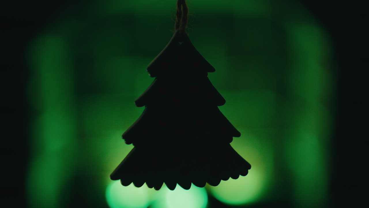 Silhouette of a small Christmas tree shape in front of a green fireplace