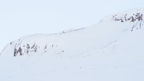 Rugged-mountains-tops-covered-in-snow-in-slow-pan-right-shot,-Iceland