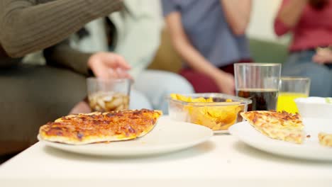 Close-up of people eating delivered pizza at home