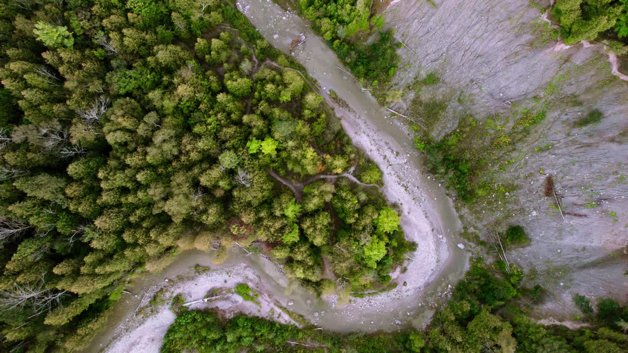 sobrecarga aérea de un río sinuoso que atraviesa un denso paisaje forestal con un acantilado erosionado, tiro ascendente