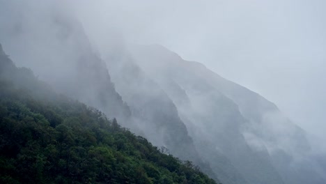 moody atmospheric mountains background with copy space, rugged dramatic mountain scenery in nepal with layers of clouds and mist in the himalayas, rocky rugged mountain background