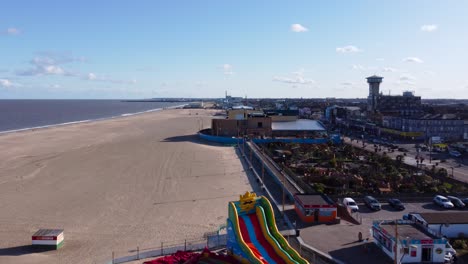 Aerial-forwarding-shot-of-inflatable-slides-on-beach-at-Great-Yarmouth,-United-Kingdom-at-daytime