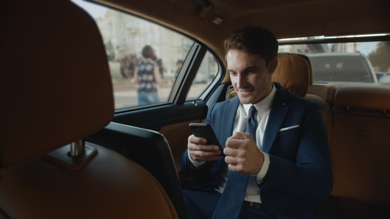Empresário surpreso recebendo boas notícias no smartphone no interior de carro moderno.