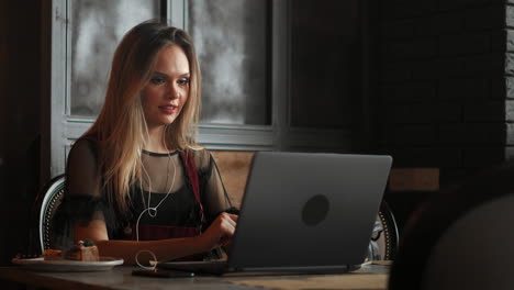 Happy-young-woman-drinking-coffee-and-using-tablet-computer-in-cafe