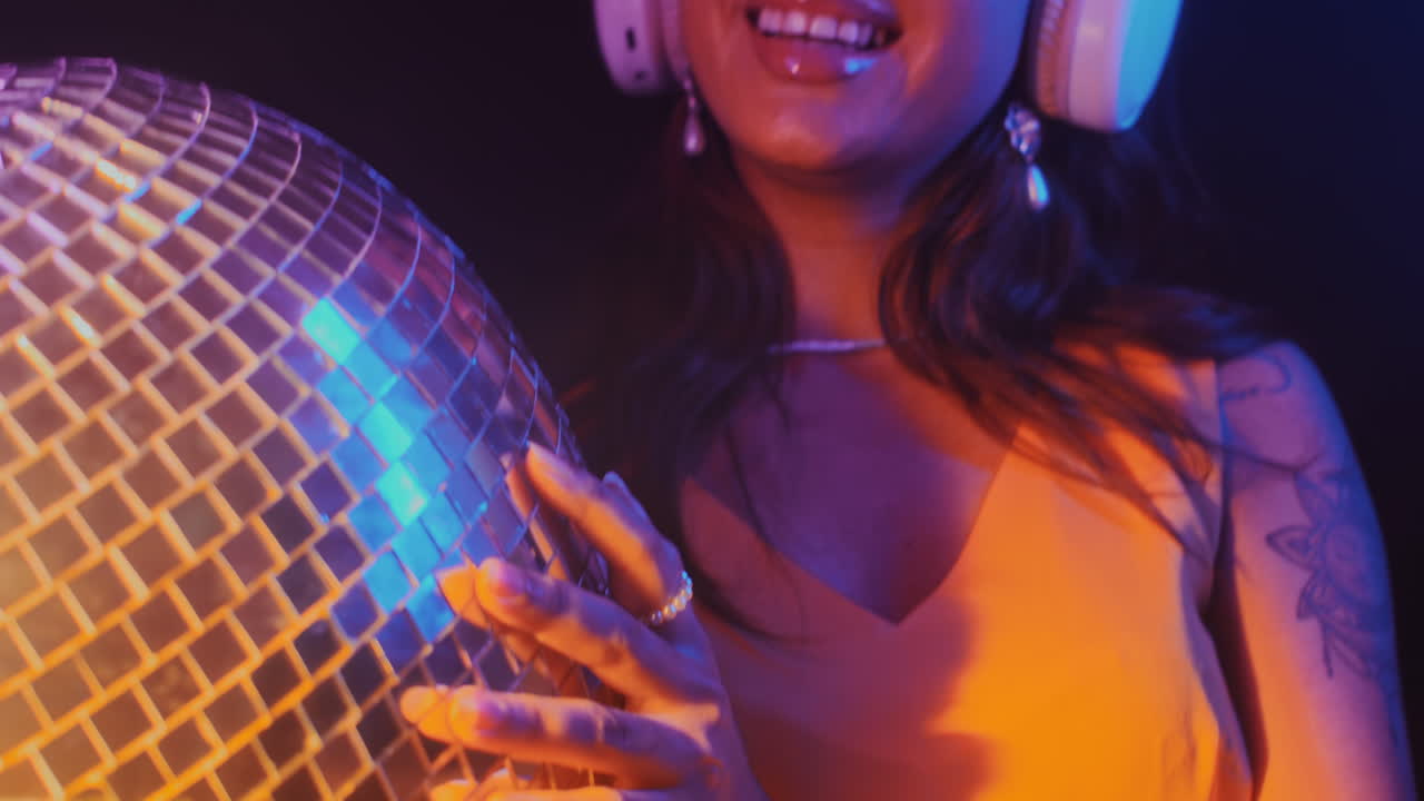 Female DJ in Headphones with Disco Ball Dancing in Club