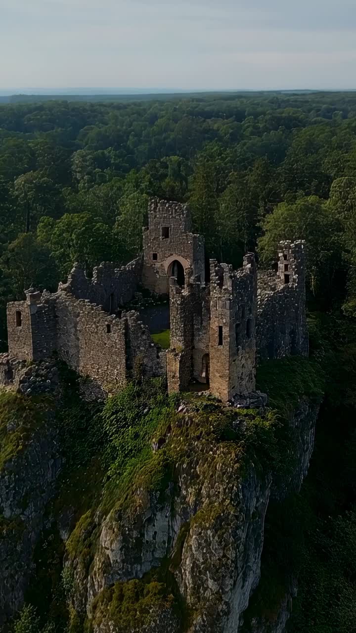 Video verticale: drone in volo che rivela le rovine di un castello in pietra su una scogliera rocciosa, mostrando i dettagli della porta