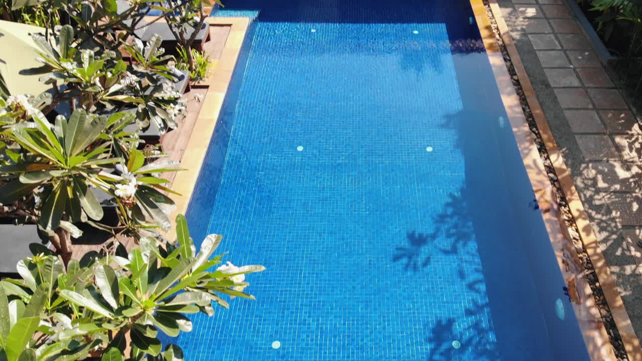 Drone-tilt-skud fra tropisk hotelswimmingpool for at afsløre restaurant- og foyerområdet