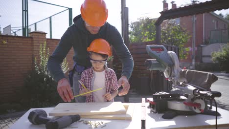 the father teaching his little son to use tools