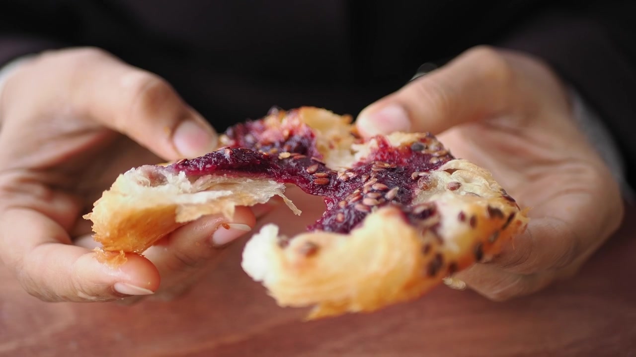 Primo piano di mani che spezzano un dolce ai frutti di bosco.