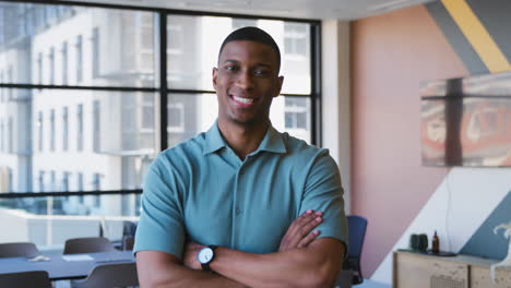 Portrait-Of-Smiling-Businessman-Standing-In-Modern-Empty-Office