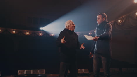 man and woman acting out quarrel with director young actress in glasses screaming at actor then throwing script and walking away while rehearsing argument scene with senior director on stage in theater
