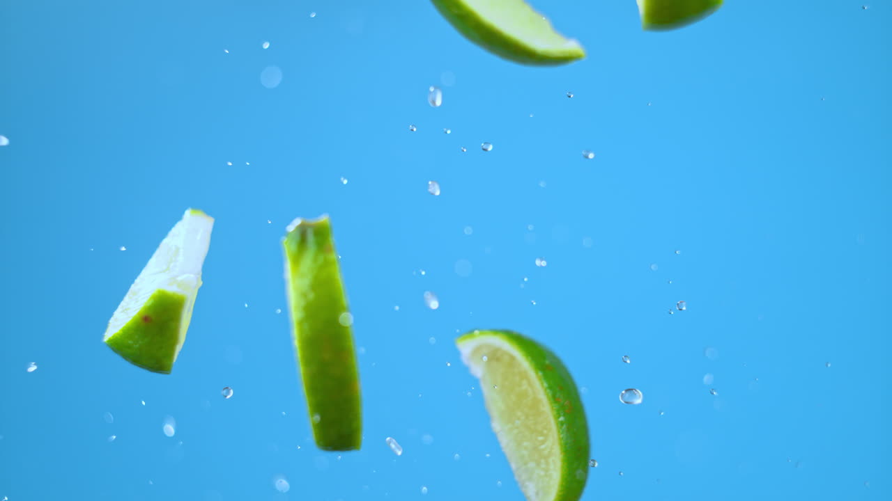 un montón de rebanadas de cal volando en el aire con agua, lanzado