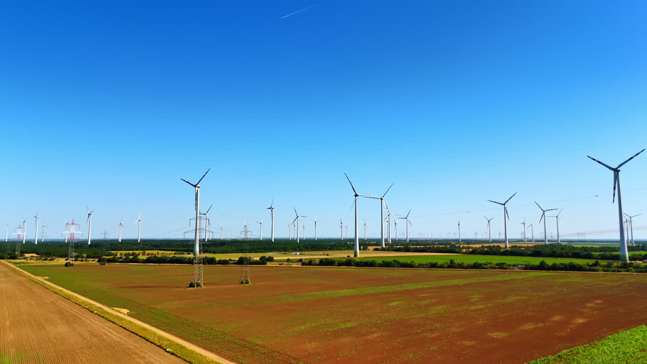 Wind turbines produce clean energy. Wind turbines spin in a vast field under a clear blue sky, contributing to renewable energy production