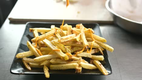 unrecognizable cook adding cheese sauce on french fries