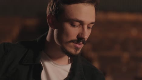 un chico guapo toca una guitarra acústica en un cine abandonado. el músico canta una canción y acompaña en la guitarra