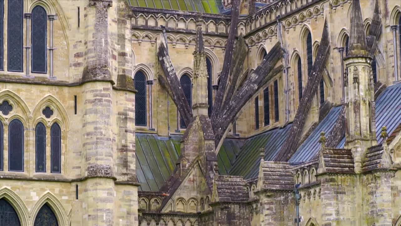 Close-up of Salisbury Cathedral’s exterior showing flying buttresses, arched windows, and stone details from the iconic medieval Gothic structure in Wiltshire, England.