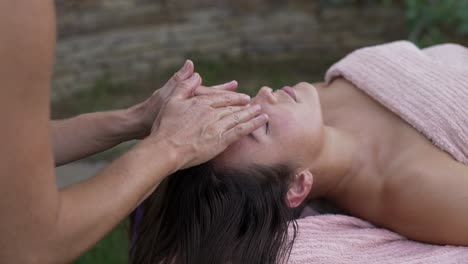 masseur rubbing face of resting patient in garden